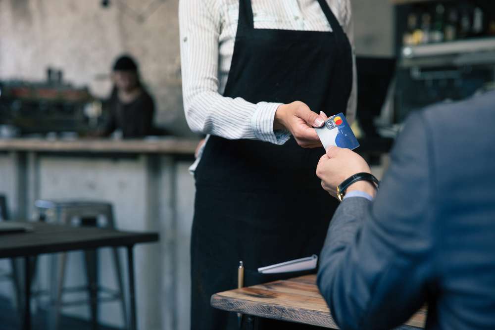 Closeup image of a man giving credit card to waiter in cafe